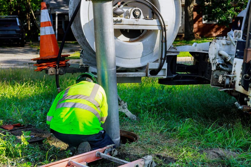 men in a yellow safety vest working on sewer line