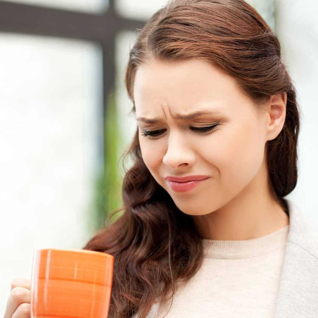 Concerned look on woman's face while looking into mug